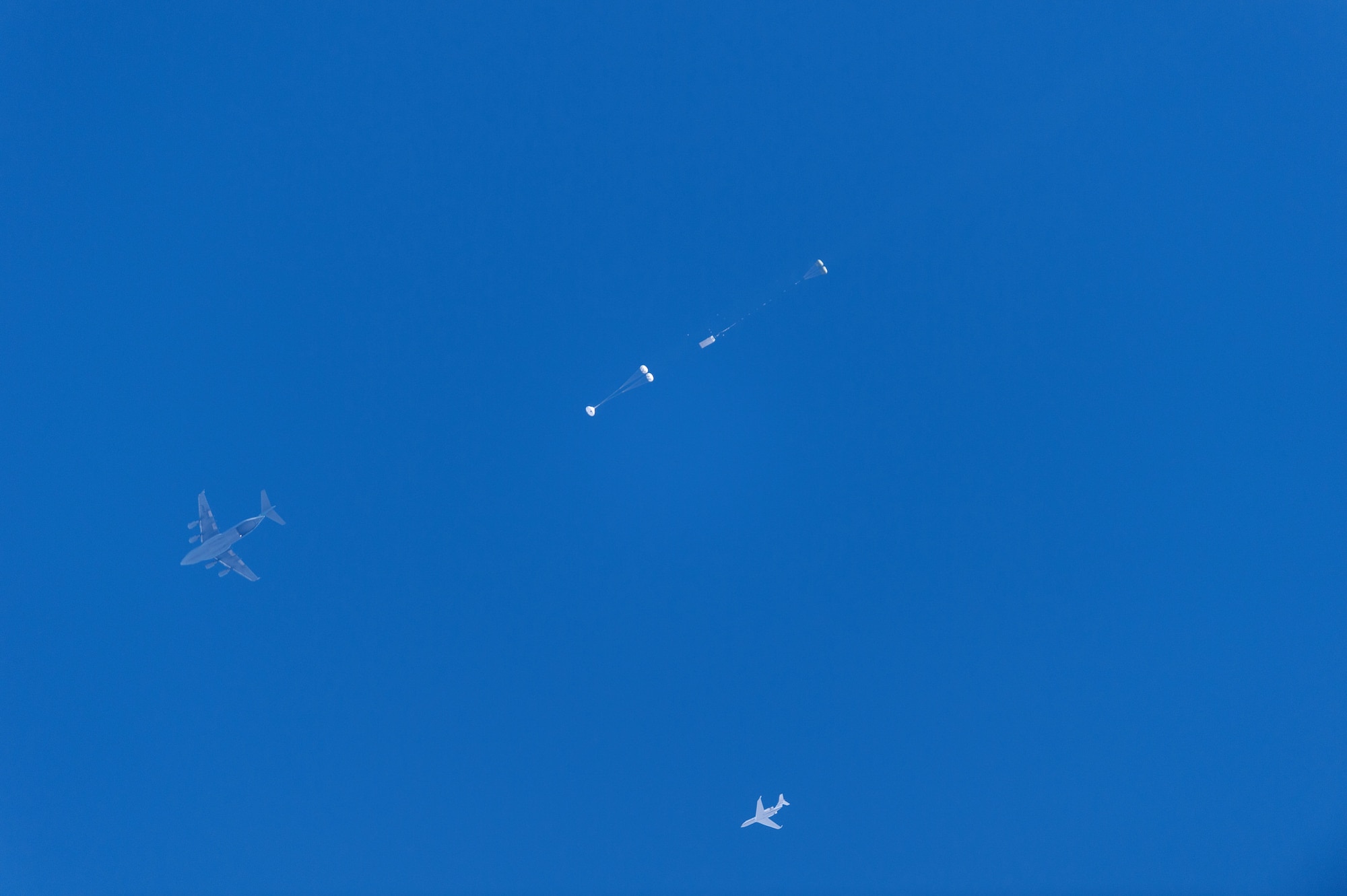 A C-17 Globemaster III and a mock Orion spacecraft fly high over Yuma, Arizona, Sept. 12, 2018.  The Orion test capsule was pulled out from the aircraft's cargo bay to perform a test of the spacecraft's parachute system. This final test qualified the parachute system for flights with astronauts, checking off an important milestone on the path to send humans on missions to the moon and beyond. (U.S. Army photo)