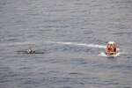 SOUTH CHINA SEA—A rigid-hulled, inflatable boat deployed off the USNS Wally Schirra (T-AKE 8) circles a distressed and adrift boat in the South China Sea, Oct. 8. Five Filipino fishermen survived for five days aboard a makeshift boat after their fishing boat sank at sea and they were rescued by the crew of USNS Wally Schirra.