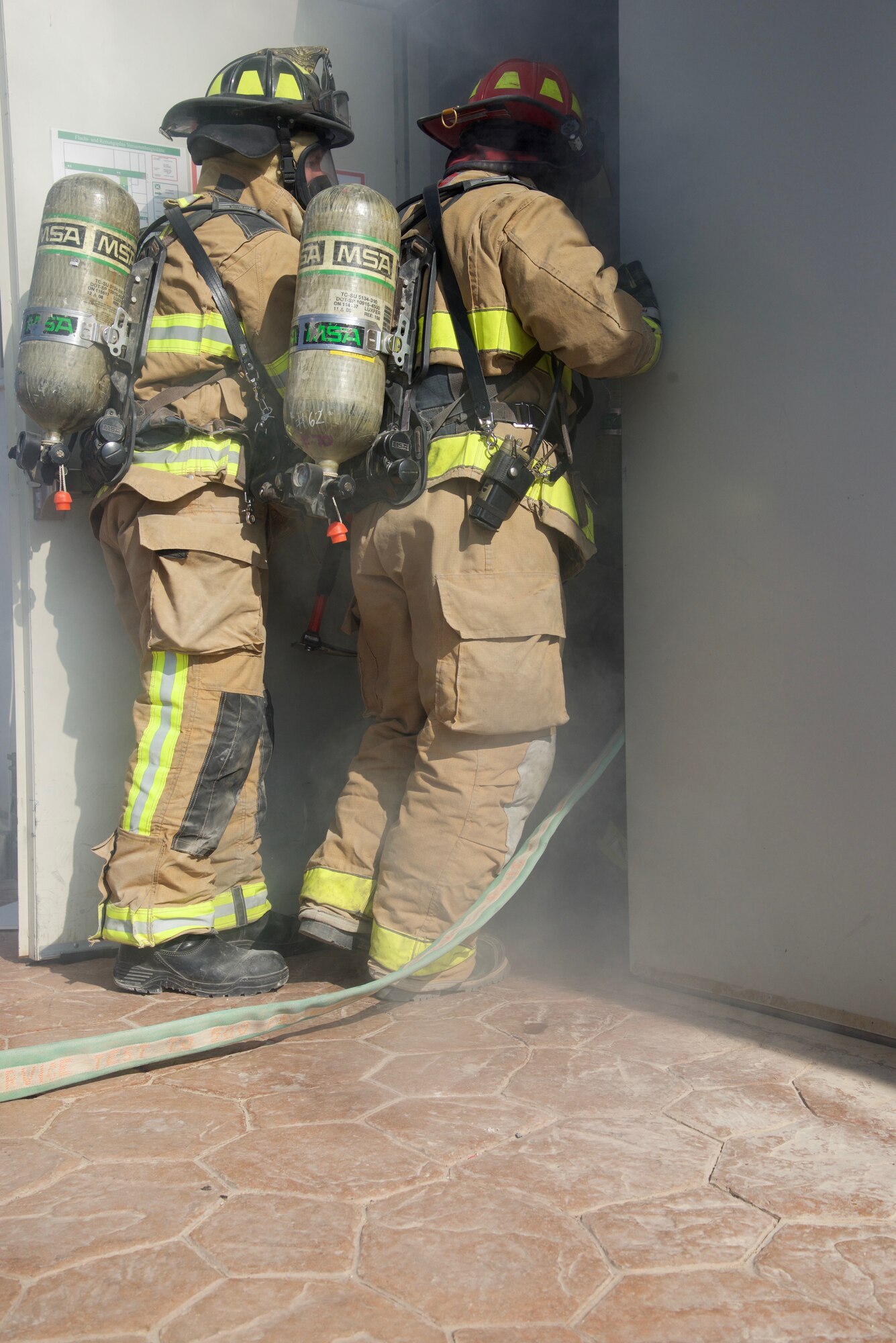 Senior Airman Justin House (left) and Staff Sgt. Vincent Kinard, 332nd Expeditionary Civil Engineer Squadron Fire Department firefighters, enter a building during a simulated fire exercise, Sept. 22, 2018, at an undisclosed location in Southwest Asia.