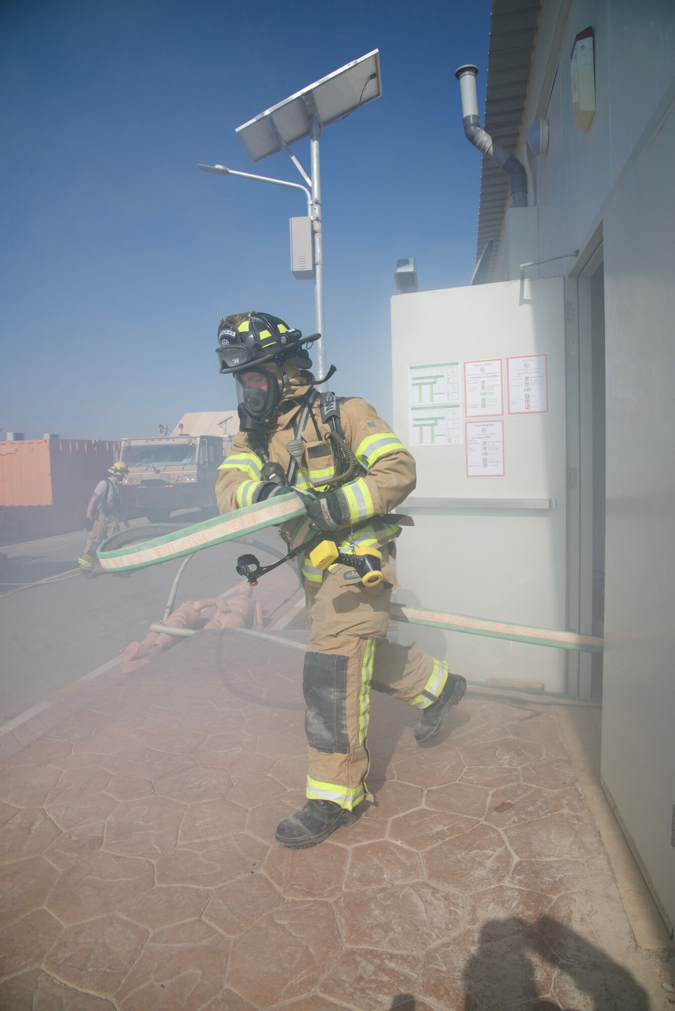 Senior Airman Justin House, 332nd Expeditionary Civil Engineer Squadron Fire Department firefighter, swings a firehose out of a building during a simulated fire exercise, Sept. 22, 2018, at an undisclosed location in Southwest Asia.