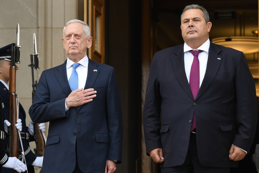 U.S. and Greek defense leaders stand at attention at the top of the Pentagon steps.
