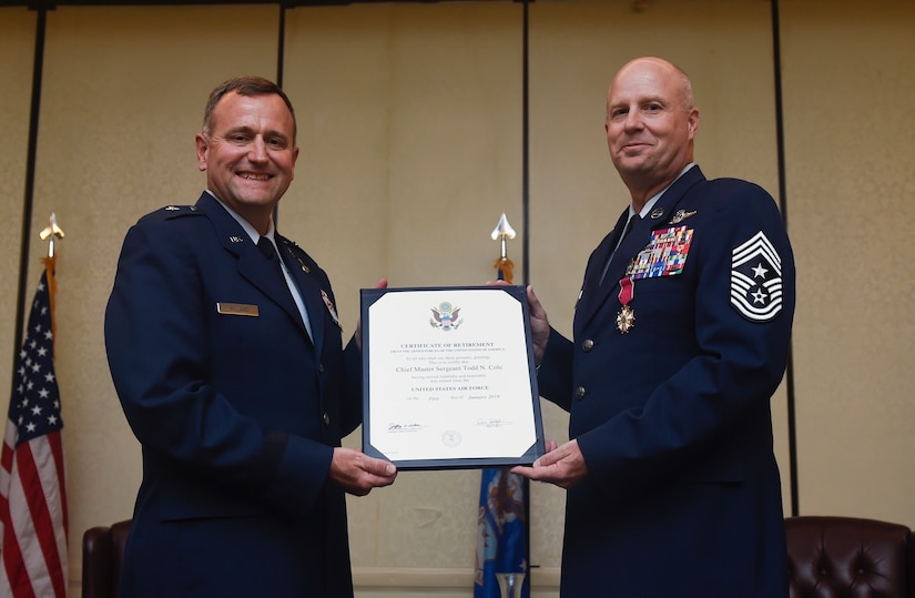 Brig. Gen. John C. Millard, Air Mobility Command deputy director of strategic plans, requirements and programs, presents Chief Master Sgt. Todd Cole, 628th Air Base Wing command chief, with his certificate of retirement Oct. 5, 2018, at Joint Base Charleston, S.C.