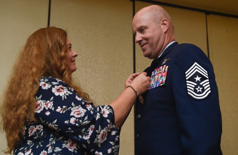 Marietta Cole, wife of Chief Master Sgt. Todd Cole, 628th Air Base Wing command chief, attaches the retirement pin on her husband’s uniform during his retirement ceremony Oct. 5, 2018, at Joint Base Charleston, S.C.