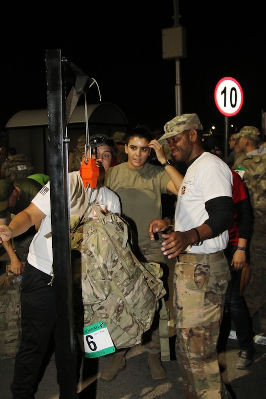 Sgt. 1st Class Brandon Brown (right) and Spc. Larissa Lopez, both with the 335th Signal Command (Theater), U.S. Army Reserve, weigh the rucksack belonging to Sgt. Brenda Sant’Ana (center), with the 151st Regional Support Group, Massachusetts Army National Guard. Competitors in the March For The Fallen–Jordan attempted to cover 28 miles in less than 11 hours while carrying 35 pounds. Marchers stepped off at 5 a.m. after event registration and a brief memorial ceremony.