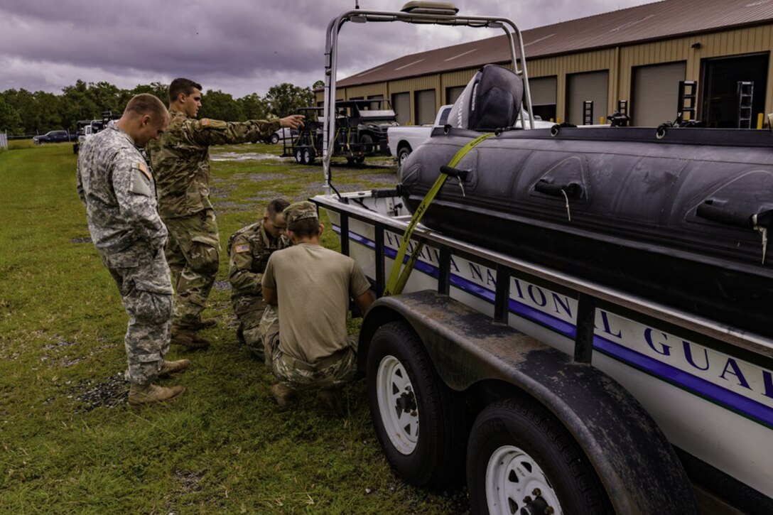 Four soldiers tie down a water craft.