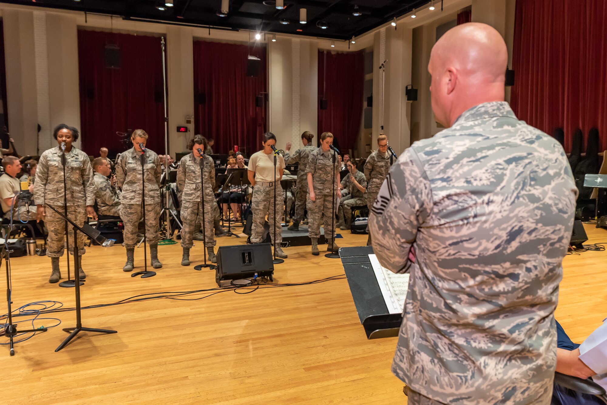 Members from the Singing Sergeants rehearse with the Concert Band while Non Commissioned Officer in Charge Senior Master Sgt. observes