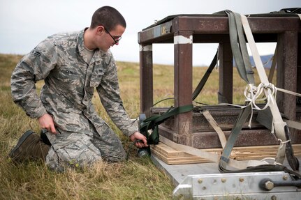 U.S. Air Force Airman 1st Class Robert Canales, a 773d Logistics Readiness Squadron combat mobility technician, secures a heavy air drop platform at the Joint Base Elmendorf-Richardson, Alaska, drop zone Oct. 3, 2018. When air drop training occurs, combat mobility technicians are called upon to operate as malfunction officers at the drop zone. In addition to scouting, technicians are also responsible to recover the loads using specific field-packing methods for secure transport back to the rigging facility.