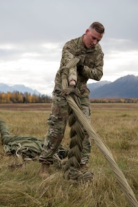 U.S. Air Force Staff Sergeant Douglas Moye, a 773d Logistics Readiness Squadron combat mobility technician supervisor, braids G-12 cargo parachute lines into a daisy chain at the Joint Base Elmendorf-Richardson, Alaska, drop zone Oct. 3, 2018. When air drop training occurs, combat mobility technicians are called upon to operate as malfunction officers at the drop zone. In addition to scouting, technicians are also responsible to recover the loads and parachutes using specific field-packing methods to keep them from getting torn or ripped.