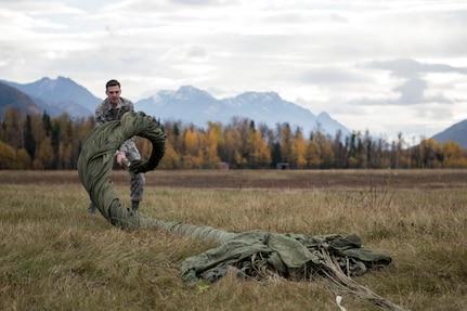 U.S. Air Force Senior Airman David Throckmorton, a 773d Logistics Readiness Squadron combat mobility technician, cigar-rolls a G-12 cargo parachute at the Joint Base Elmendorf-Richardson, Alaska, drop zone Oct. 3, 2018. When air drop training occurs, combat mobility technicians are called upon to operate as malfunction officers at the drop zone. In addition to scouting, technicians are also responsible to recover the loads and parachutes using specific packing methods to keep them from getting torn or ripped.