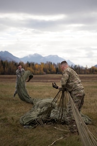 U.S. Air Force Staff Sergeant Douglas Moye, a 773d Logistics Readiness Squadron combat mobility technician supervisor and Senior Airman David Throckmorton, a 773d LRS combat mobility technician maneuver a G-12 cargo parachute at the Joint Base Elmendorf-Richardson, Alaska, drop zone Oct. 3, 2018. When air drop training occurs, combat mobility technicians are called upon to operate as malfunction officers at the drop zone. In addition to scouting, technicians are also responsible to recover the loads and parachutes using specific packing methods to keep them from getting torn or ripped.
