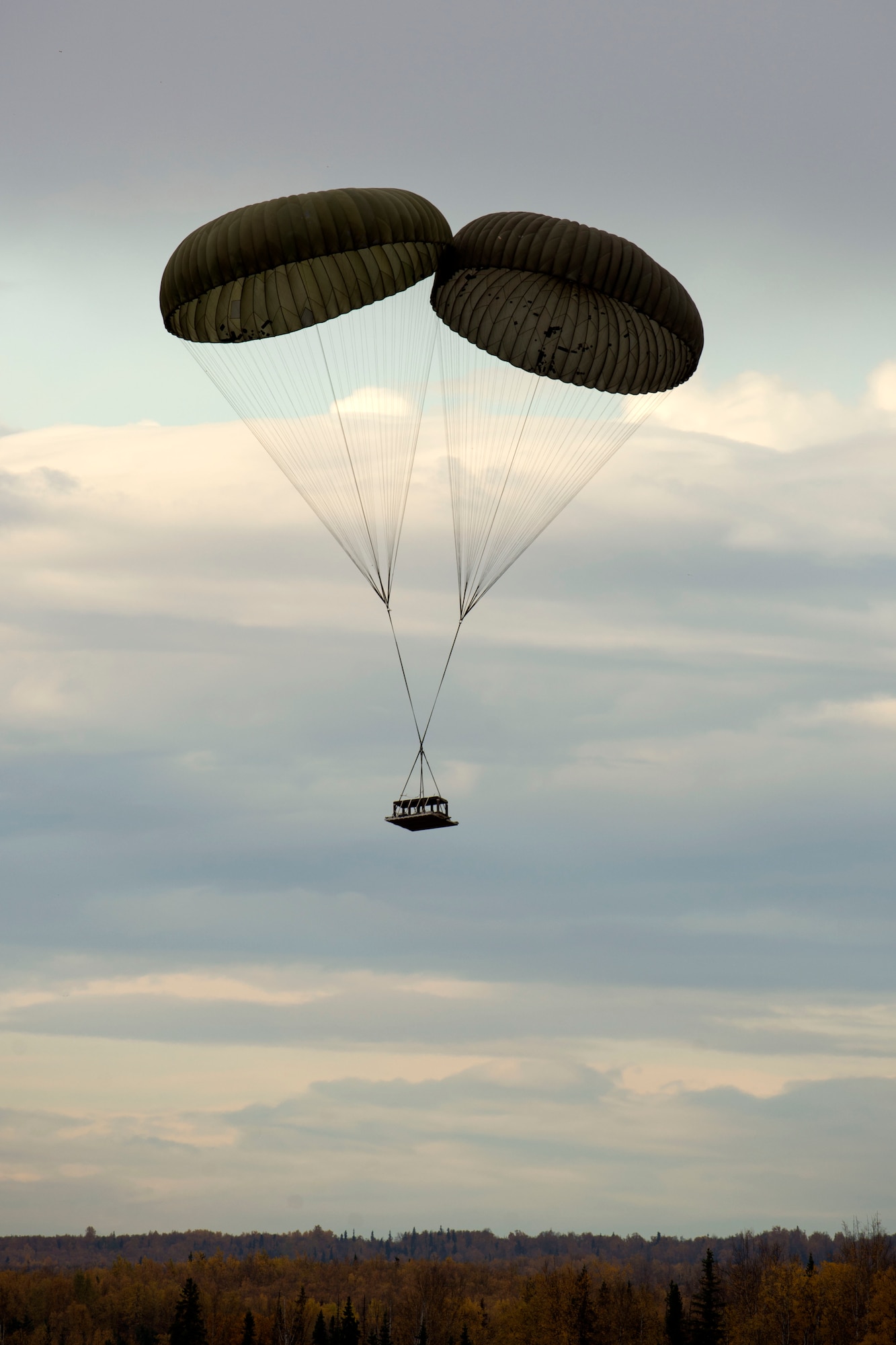 A heavy drop platform falls from the sky during air drop qualification training at Joint Base Elmendorf-Richardson, Alaska, Oct. 3, 2018. Two G-12 cargo parachutes were used for this heavy load weighing 3,700 pounds. When air drop training occurs, combat mobility technicians from the 773d Logistics Readiness Squadron are called upon to operate as malfunction officers at the drop zone.