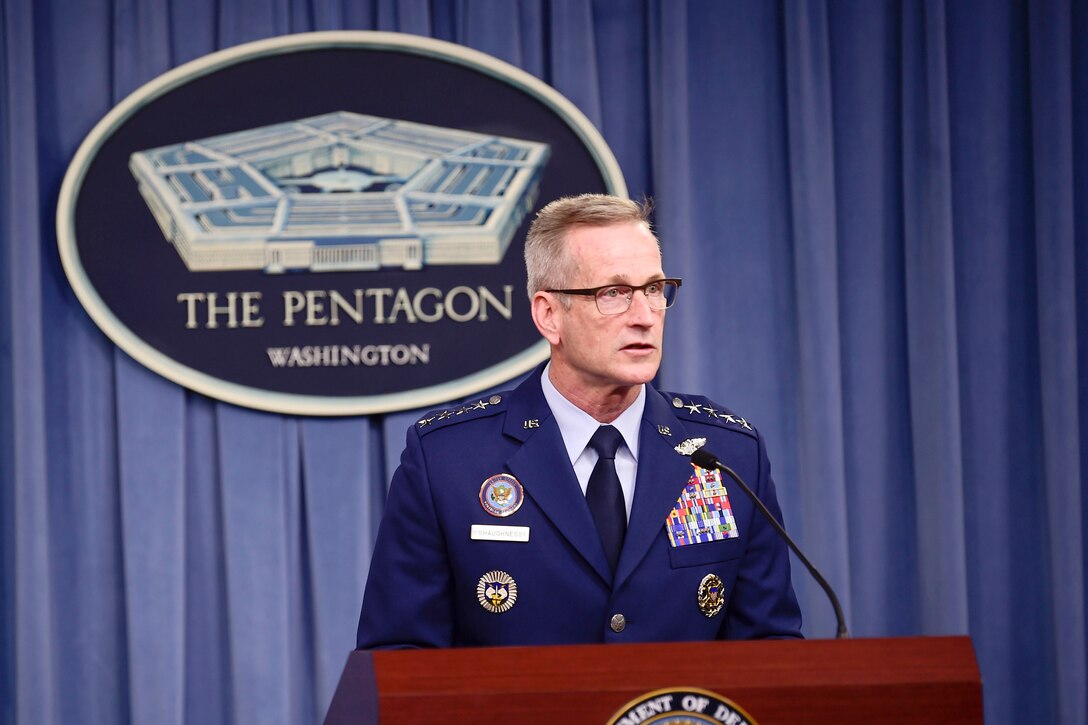 The U.S. Northern Command commander speaks at a lectern in front of a blue curtain with a Pentagon seal.