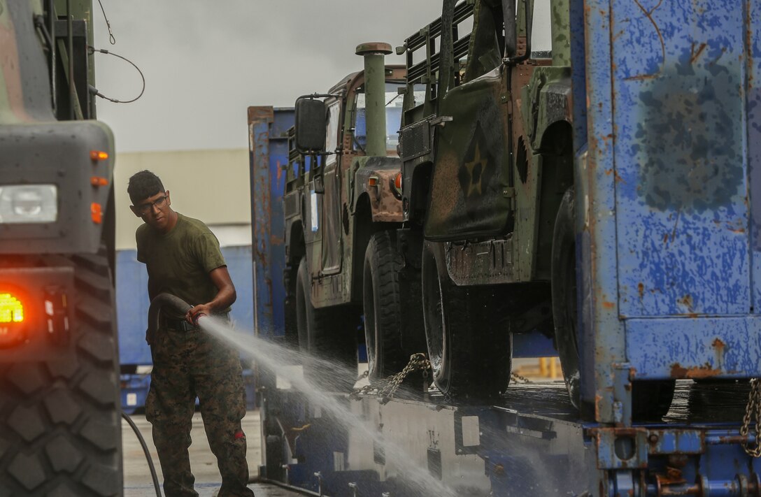 A U.S. Marine with II Marine Expeditionary Force sprays off a trailer before storing them on USNS Wright (T-AVB 3) before embarkation to Norway at the Port of Morehead City in Beaufort, N.C., Sept. 28, 2018. These vehicles will be used as part of II MEFs participation in the NATO-led Exercise Trident Juncture 18 in Norway, Sweden, Finland, and Iceland. Trident Juncture 18 enhances the U.S. and NATO Allies’ abilities to work together collectively to conduct military operations under challenging conditions. Trident Juncture will include more than 14,000 U.S. service members and 31 Allied and partner nations, totaling more than 40,000 NATO troops. (U.S. Marine Corps photo by Lance Cpl. Samuel Lyden)
