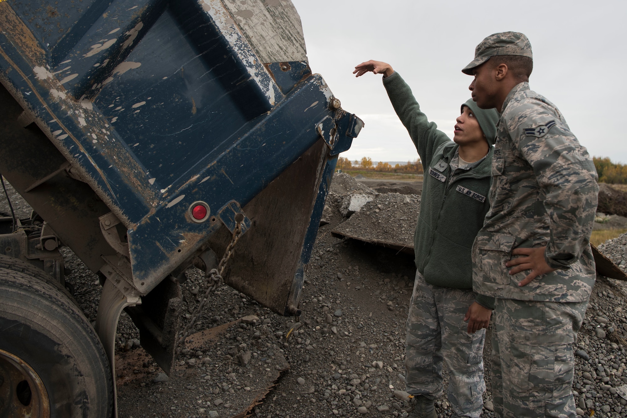 U.S. Air Force Airman 1st Class Isaiah Torres, 773d Civil Engineer Squadron pavement and construction operator, explains the proper methods of unloading a dump truck to Airman 1st Class Shane Leaphart, 773d CES engineer assistant, at Joint Base Elmendorf-Richardson, Alaska, Oct. 3, 2018. The 773d CES snow barn personnel train augmentees on properly operating snow-removal equipment, in preparation for the coming winter.