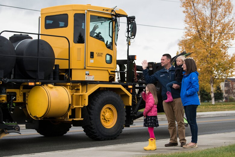 A Joint Base Elmendorf-Richardson family waves at a passing snow-removal vehicle during the annual Snow and Ice Parade at JBER, Alaska, Oct. 4, 2018. The 773d Civil Engineer Squadron snow barn hosts the event to signal the coming of winter.