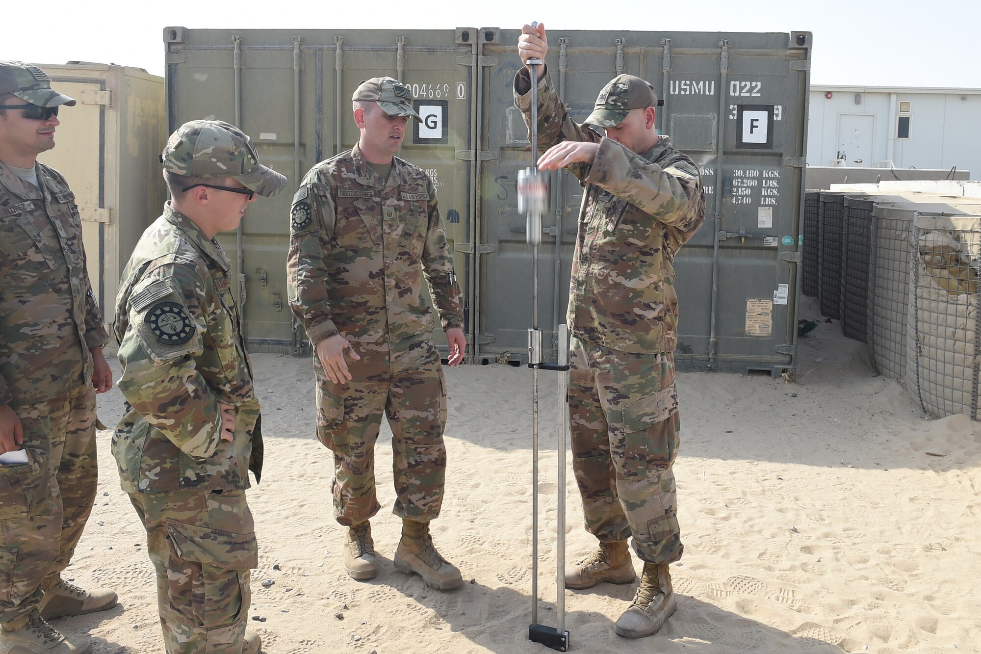 Three Airmen use an engineering tool outside.