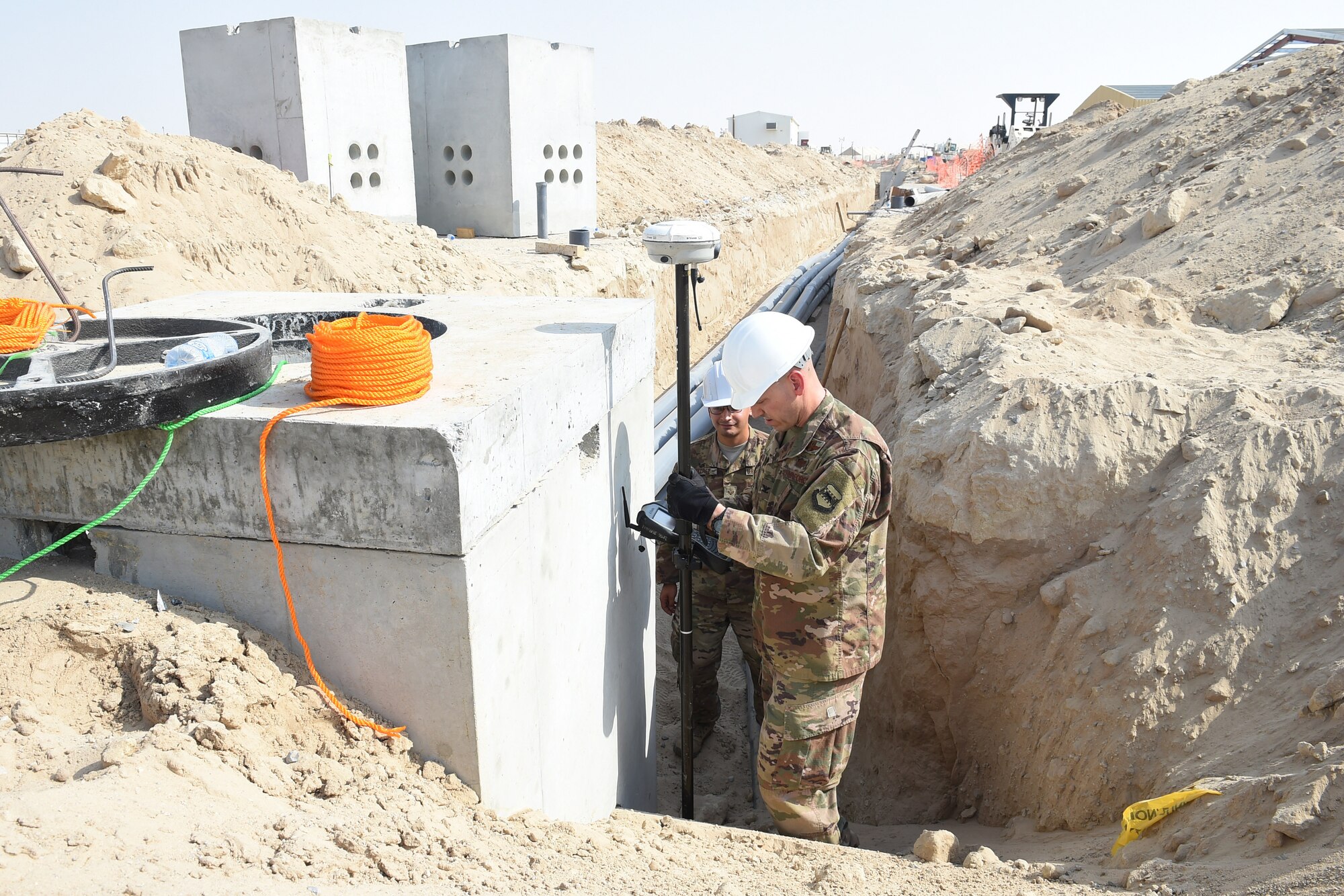 Three Airmen use an engineering tool outside.