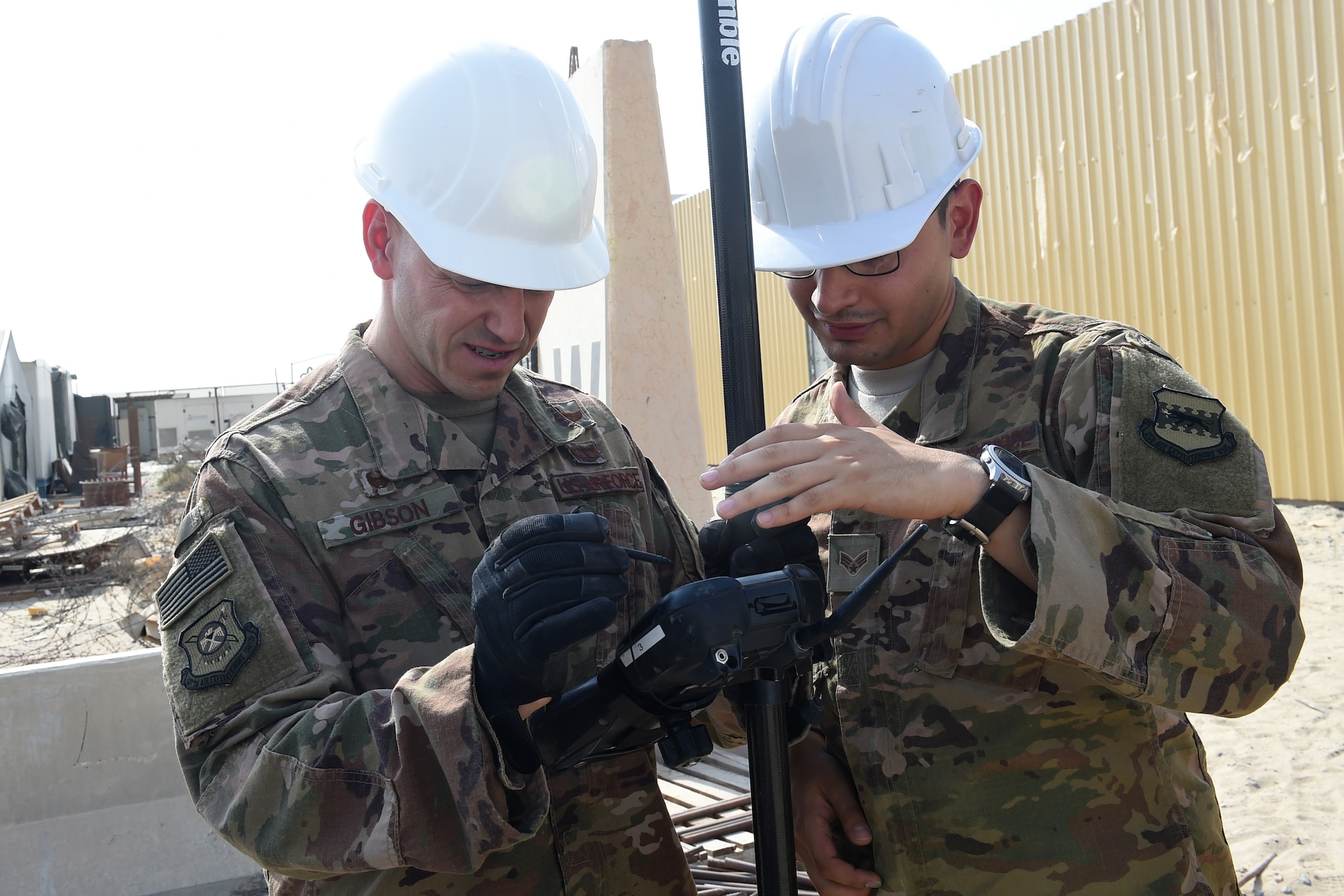 Three Airmen use an engineering tool outside.