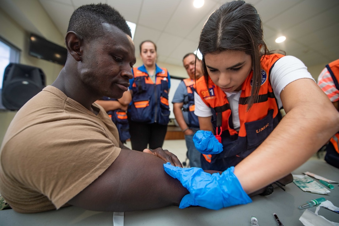 A U.S. Navy Hospital Corpsman participates in an intravenous application at a Comite Permanente de Contingencias (COPECO) facility as part of a subject matter expert exchange with Honduran emergency response medical personnel.