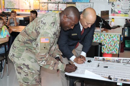 Col. Isaac Manigault (left), commander of the U.S. Army Environmental Command, and Dr. Joseph Cerna, Fort Sam Houston Elementary School principal, sign a renewal of the official charter for the Joint Base San Antonio-Fort Sam Houston Adopt-A-School Program partnership Oct. 3.