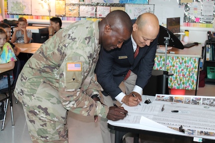 Col. Isaac Manigault (left), commander of the U.S. Army Environmental Command, and Dr. Joseph Cerna, Fort Sam Houston Elementary School principal, sign a renewal of the official charter for the Joint Base San Antonio-Fort Sam Houston Adopt-A-School Program partnership Oct. 3.