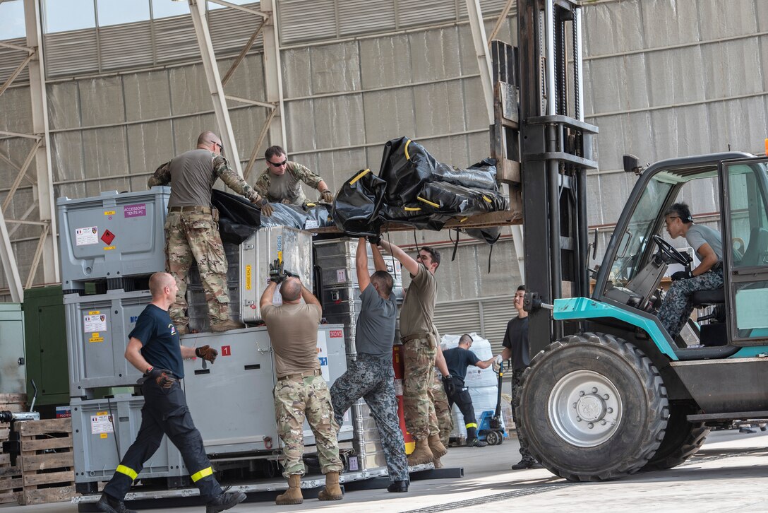 U.S. Air Force members assigned to the 36th Contingency Response Group Andersen Air Force Base, Guam, Japan Air Self-Defense Force and French military members load cargo on a forklift in Balikpapan, Indonesia Oct. 9, 2018.