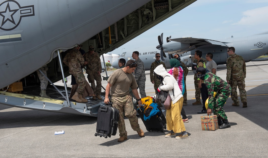 U.S. Air Force Staff Sgt. Roni Choueiry, 36th Contingency Response Group NCO in charge standards and evaluation, at Andersen Air Force Base, Guam helps an Indonesian woman with her luggage after a flight on a C-130 Hercules aircraft in Balikpapan, Indonesia Oct. 9, 2018.