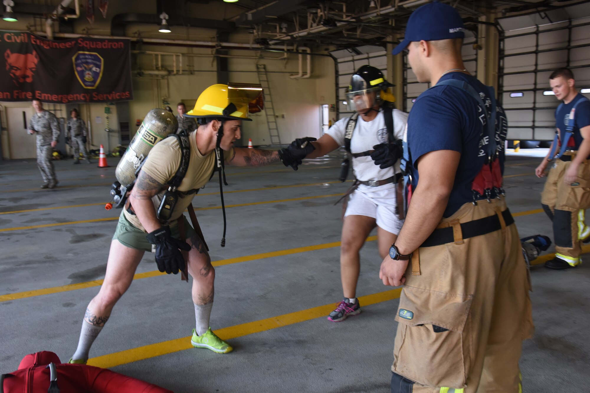 U.S Air Force Senior Master Sgt. Ira Jack, center, 51st Civil Engineer Squadron 1st Sgt., hands a baton to Master Sgt. Layne Mayerstein, 51st Civil Engineer Squadron Explosive Ordinance Disposal flight chief, as Staff Sgt. Jonathan Martinez and Airman Joseph Jenkins, 51st Civil Engineer Squadron fire and emergency services flight firefighters, watch for safety precautions during the Eagles and Commanders versus Chiefs and Shirts Fire Muster at Osan Air Base, Republic of Korea, Oct. 12, 2018. The relay, which included six stations such as ladder climbing and fire hose pulling, was part of Fire Prevention Week, which was held 9 through 13 Oct. (U.S. Air Force photo by Tech. Sgt. Ashley Tyler)