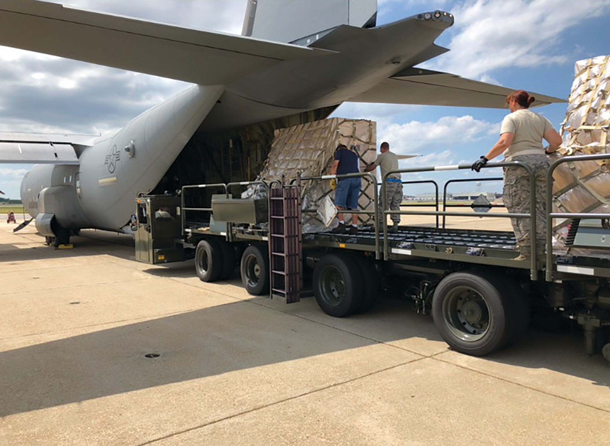 87th Aerial Port Squadron Airmen help move a pallet with the help of their civilian Naval counterparts onto the back of a cargo plane at Norfolk Naval Air Station's Navy Operated Air Mobility Command Terminal as part of the Patriot Partner Exercise held July 6-20, 2018.