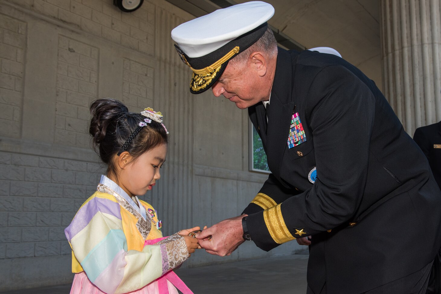 JEJU ISLAND, Republic of Korea, (Oct. 12, 2018) Rear Adm. Michael E. Boyle, commander, U.S. Naval Forces Korea (CNFK) presents a coin to a young girl during a welcome ceremony at the Republic of Korea (ROK) Navy base in Jeju. CNFK is the U.S. Navy's representative in the ROK, providing leadership and expertise in naval matters to improve institutional and operational effectiveness between the two navies and to strengthen collective security efforts in Korea and the region.