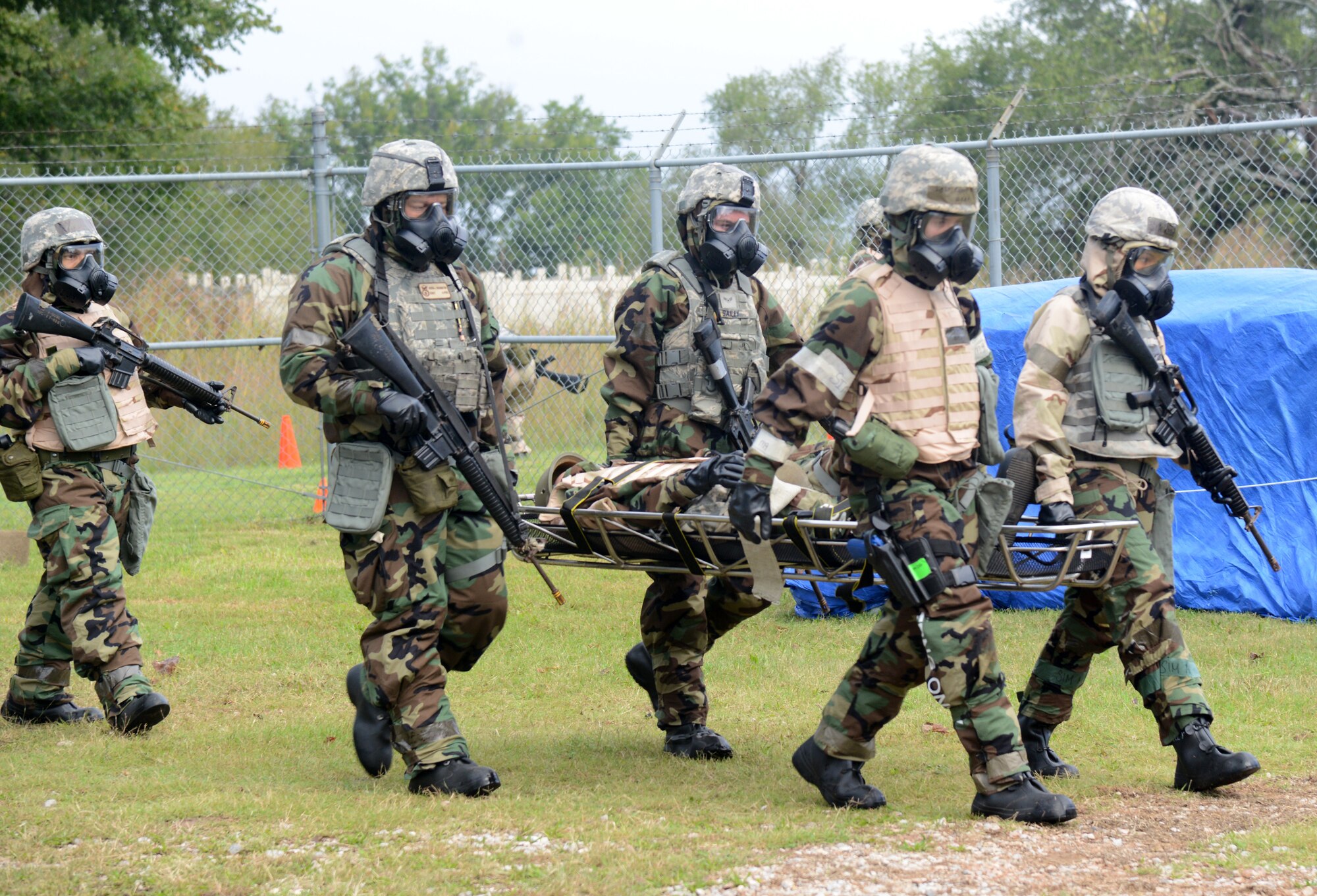 A team participating in the CBRNE exercise carry an injured dummy on a litter to a checkpoint after administering self-aid buddy care. Knowing how to correctly assess injuries, whether critical or fatal, and then help the wounded victim without creating more harm, is an important component during these kinds of exercises.