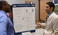 IMAGE: KING GEORGE, Va. (Sept. 25, 2018) – Principal investigator Dr. Michael Lowry briefs a visitor at the Naval Surface Warfare Center Dahlgren Division (NSWCDD) In-house Laboratory Independent Research (ILIR) and Independent Applied Research (IAR) End of Year Review at the University of Mary Washington Dahlgren Campus. Lowry -- an NSWCDD chemist who researches the interaction between matter and radiation across the electromagnetic spectrum -- explained his ILIR project, “Modulating Electronic Properties of Two Dimensional Macromolecular Structures Through Additives and Post-Synthetic Modification” to Navy technical managers, engineers, and scientists as well as representatives from academia, industry, transition partners, and other key stakeholders. Funded by the Office of Naval Research, the ILIR and IAR program fosters fundamental and applied research at the Navy Warfare Centers to counter emerging threats by connecting technological needs with current and emerging capabilities.