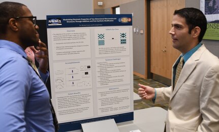 IMAGE: KING GEORGE, Va. (Sept. 25, 2018) – Principal investigator Dr. Michael Lowry briefs a visitor at the Naval Surface Warfare Center Dahlgren Division (NSWCDD) In-house Laboratory Independent Research (ILIR) and Independent Applied Research (IAR) End of Year Review at the University of Mary Washington Dahlgren Campus. Lowry -- an NSWCDD chemist who researches the interaction between matter and radiation across the electromagnetic spectrum -- explained his ILIR project, “Modulating Electronic Properties of Two Dimensional Macromolecular Structures Through Additives and Post-Synthetic Modification” to Navy technical managers, engineers, and scientists as well as representatives from academia, industry, transition partners, and other key stakeholders. Funded by the Office of Naval Research, the ILIR and IAR program fosters fundamental and applied research at the Navy Warfare Centers to counter emerging threats by connecting technological needs with current and emerging capabilities.