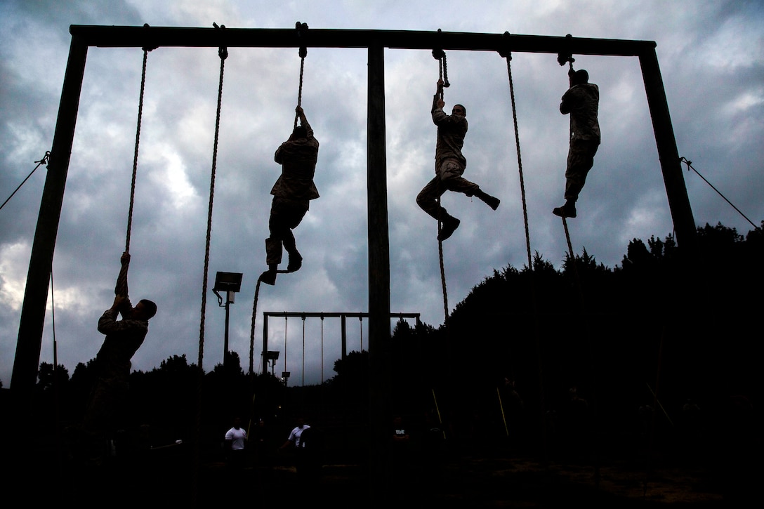 Four Marines climb a rope obstacle.