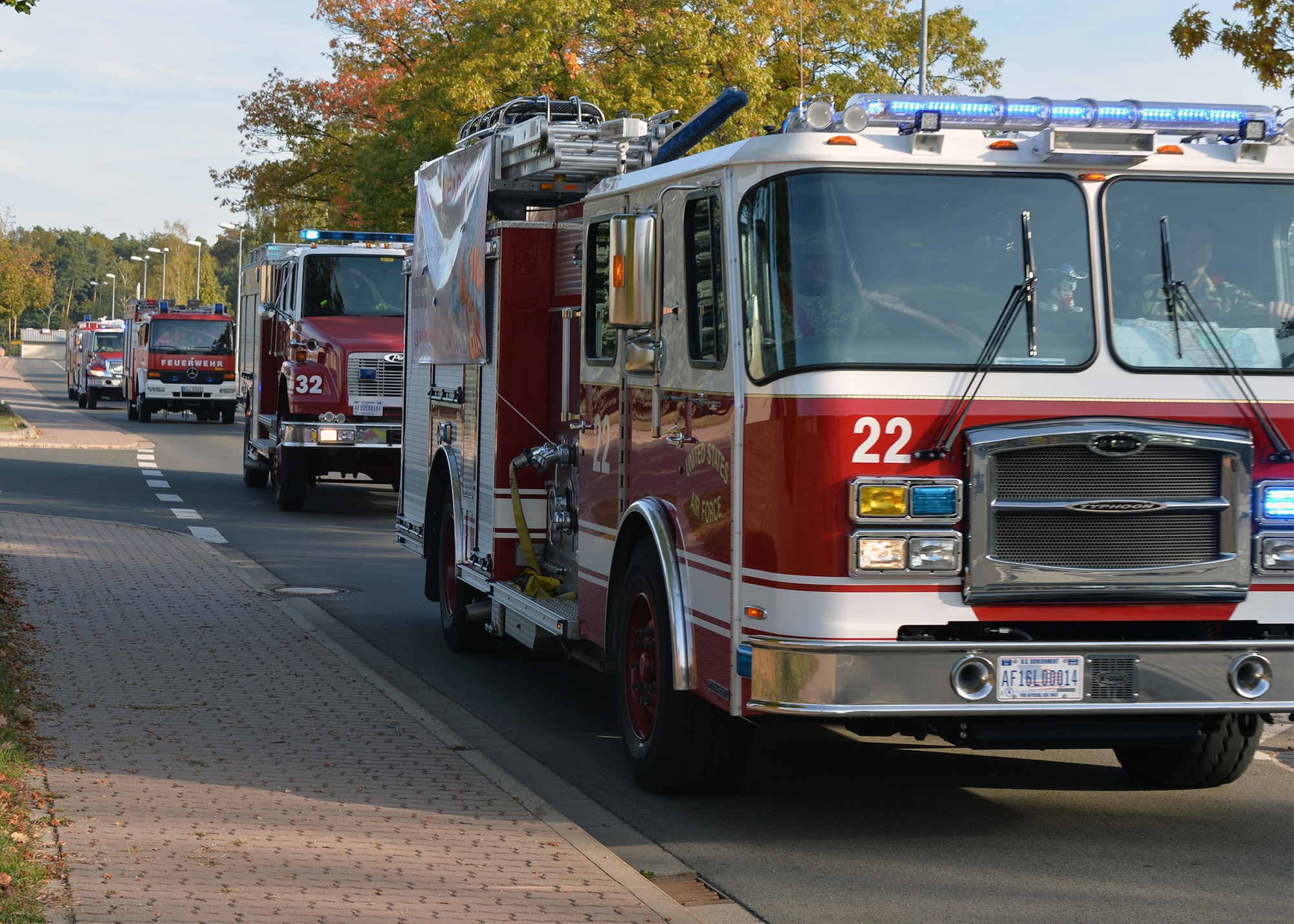 Firefighters from the Kaiserslautern Military Community Fire and Emergency Services drive fire trucks by base housing on Ramstein Air Base, Germany, Oct. 6, 2018. Fire trucks were part of a parade to kick off Fire Prevention Week on Ramstein, observed from Oct. 7 - 13. (U.S. Air Force photo by Staff Sgt. Jimmie D. Pike)