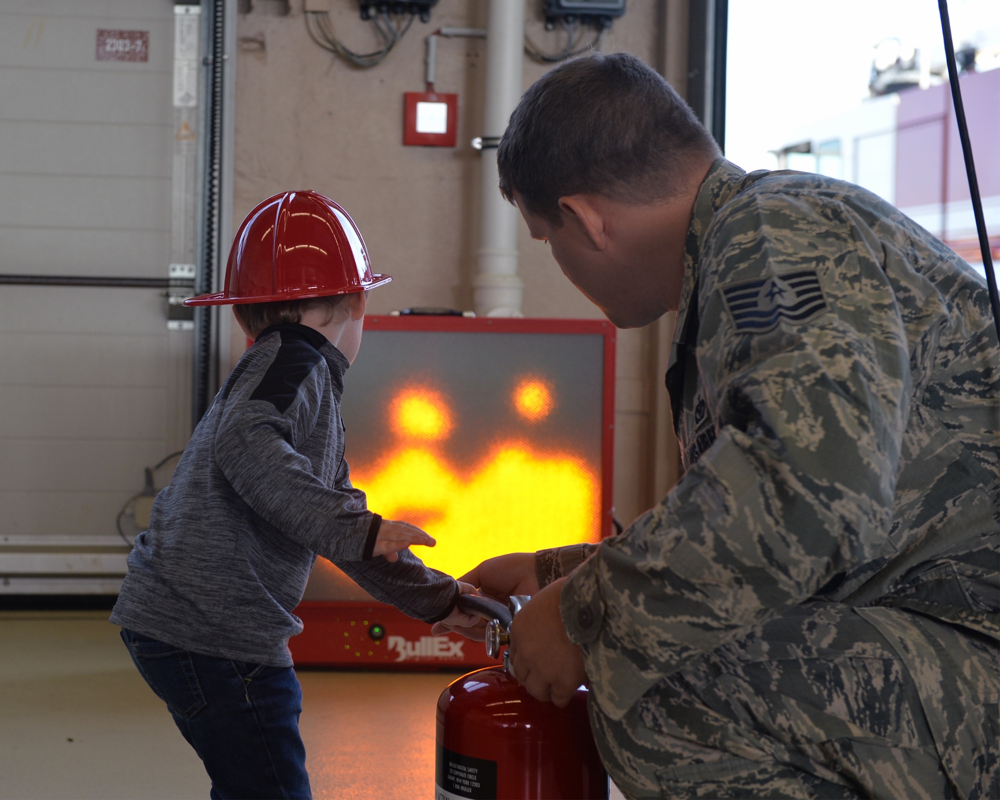 U.S. Air Force Tech. Sgt. James Fligor, 86th Civil Engineer Squadron Station 3 station chief, helps a child put out a simulated fire on a fire extinguisher trainer on Ramstein Air Base, Germany, Oct. 6, 2018. Members of the Kaiserslautern Military Community Fire and Emergency Services came together during Fire Prevention Week to help raise awareness of the importance of fire safety. (U.S. Air Force photo by Staff Sgt. Jimmie D. Pike)