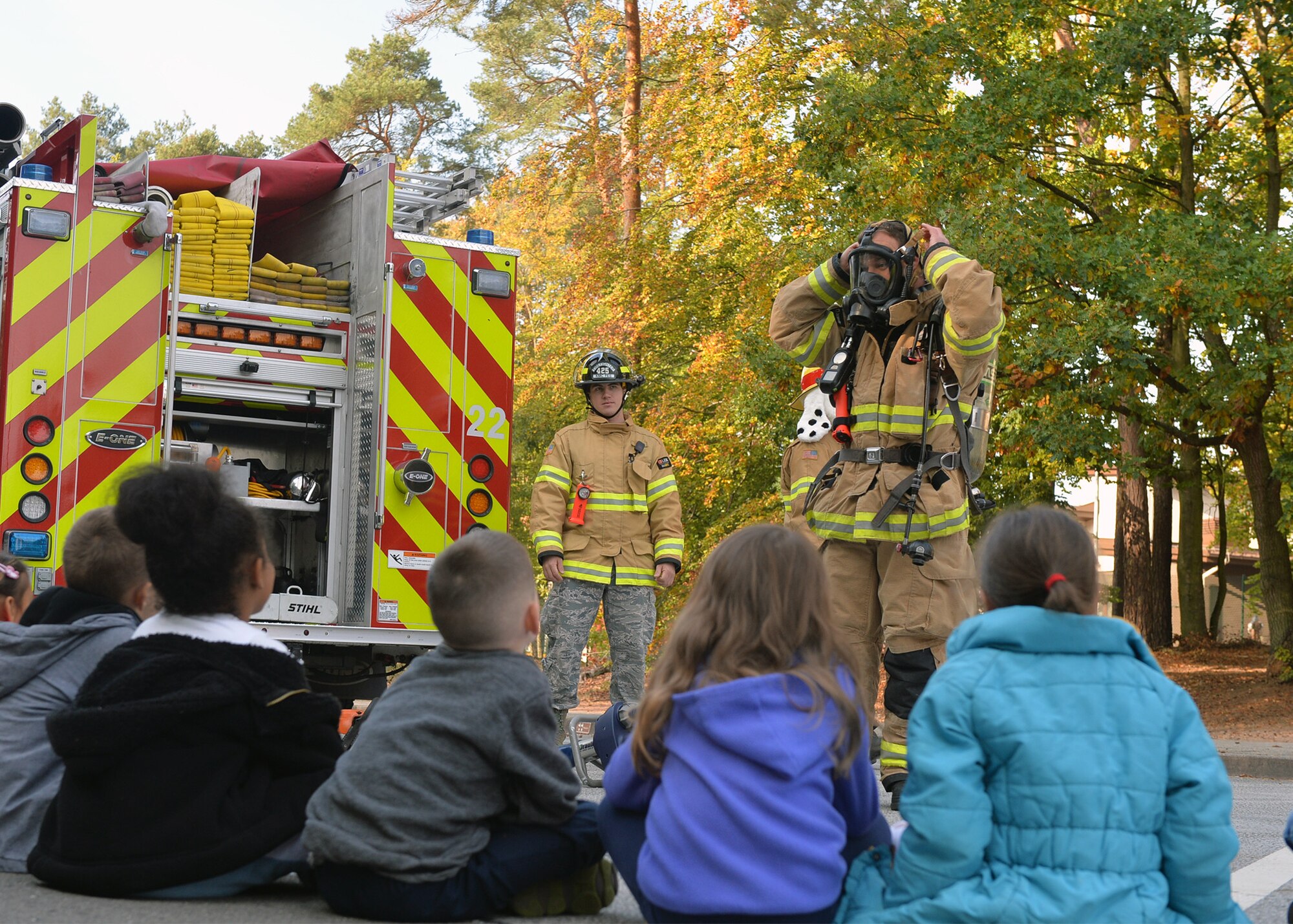 Sascha Rech, 86th Civil Engineer Squadron lead firefighter, displays how firefighters look in their gear to children on Ramstein Air Base, Germany, Oct. 9, 2018. Familiarity with firefighters can help prevent children from being scared of responders during a fire emergency. (U.S. Air Force photo by Staff Sgt. Jimmie D. Pike)