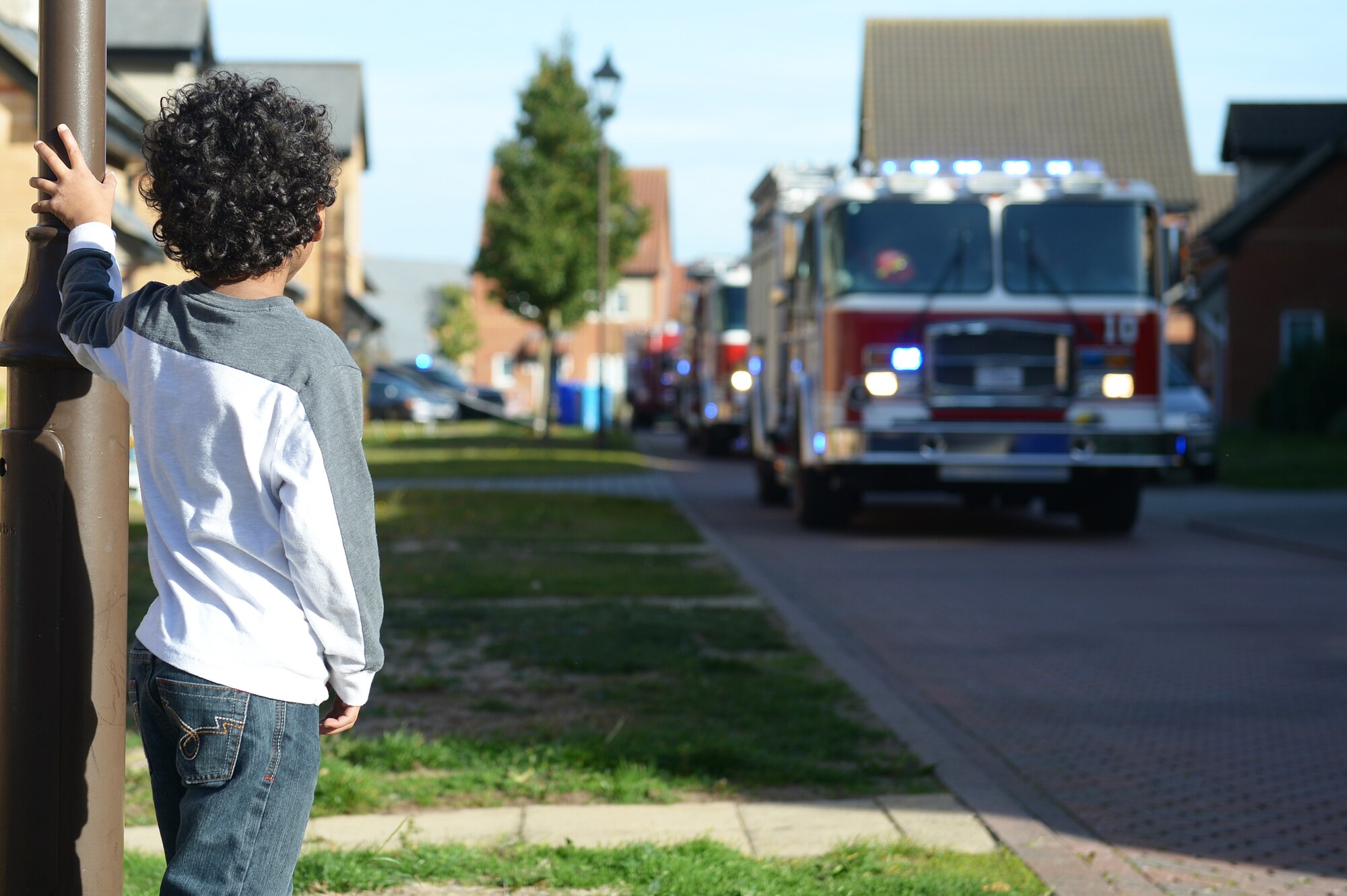 A child observes a fire truck parade at Royal Air Force Lakenheath, England, Oct.12, 2018. The 48th Civil Engineer Squadron hosted several events throughout the week in recognition of Fire Prevention Week. (U.S.Air Force photo/Airman 1st Class Shanice Williams-Jones)