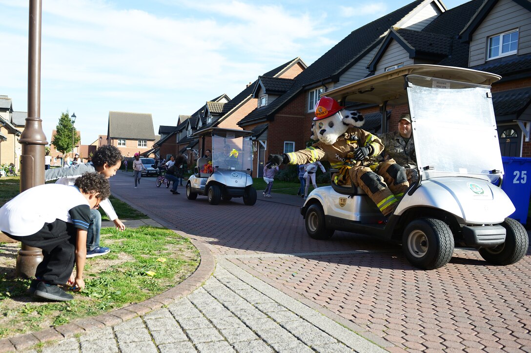 Sparky the Fire Dog throws candy to children during a fire truck parade at Royal Air Force Lakenheath, England, Oct.12, 2018. Sparky helped the 48th Civil Engineer Airmen teach children how to look around their home, identify potential fire hazards and take care of them.  (U.S.Air Force photo/Airman 1st Class Shanice Williams-Jones)