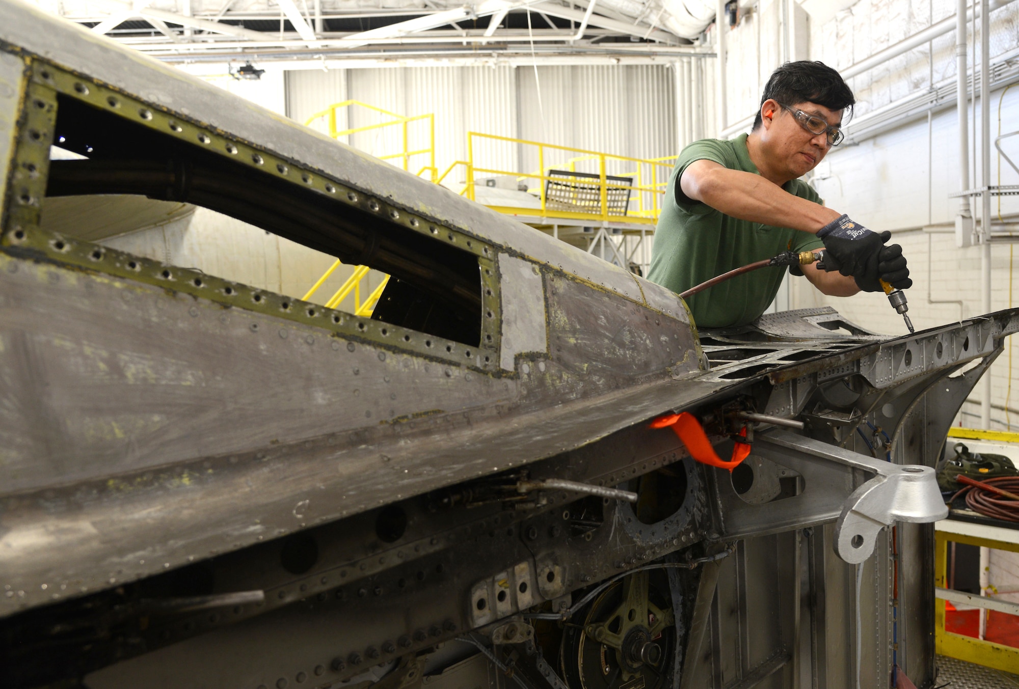 Khoi Le, a sheetmetal mechanic with the 565th Aircraft Maintenance Squadron, drills rivets into an engine strut of a B-52 Stratofortress as part of programmed depot maintenance.