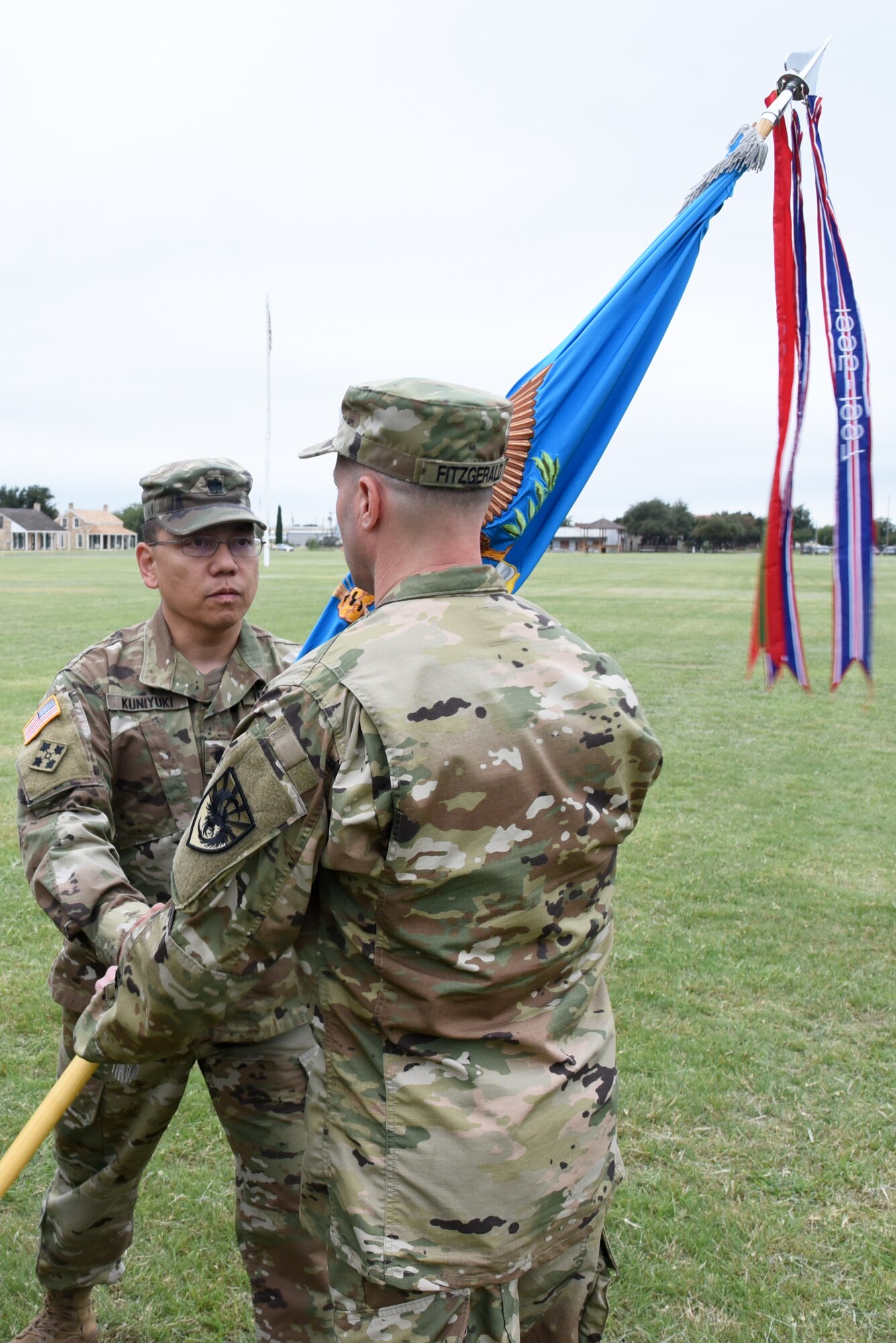 U.S. Army Lt. Col. Yukio Kuniyuki III, 344th Military Intelligence Battalion outgoing commander, passes the 344th MI BN guideon to Col. Scott Fitzgerald, 111th Military Intelligence Brigade commander, during the 344th MI BN Change of Command at the Fort Concho parade field in San Angelo, Texas, Oct. 12, 2018. The passing of the guideon signifies the passing of command authority from one commander to the next. (U.S. Air Force photo by Staff Sgt. Joshua Edwards/Released)