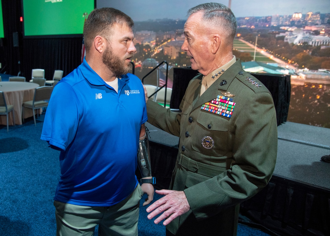 Marine Corps Gen. Joe Dunford, chairman of the Joint Chiefs of Staff, speaks to retired Army Staff Sgt. Travis Mills, Founder of the Travis Mills Foundation, during the New England Council Annual Dinner at the Seaport Hotel and World Trade Center in Boston.