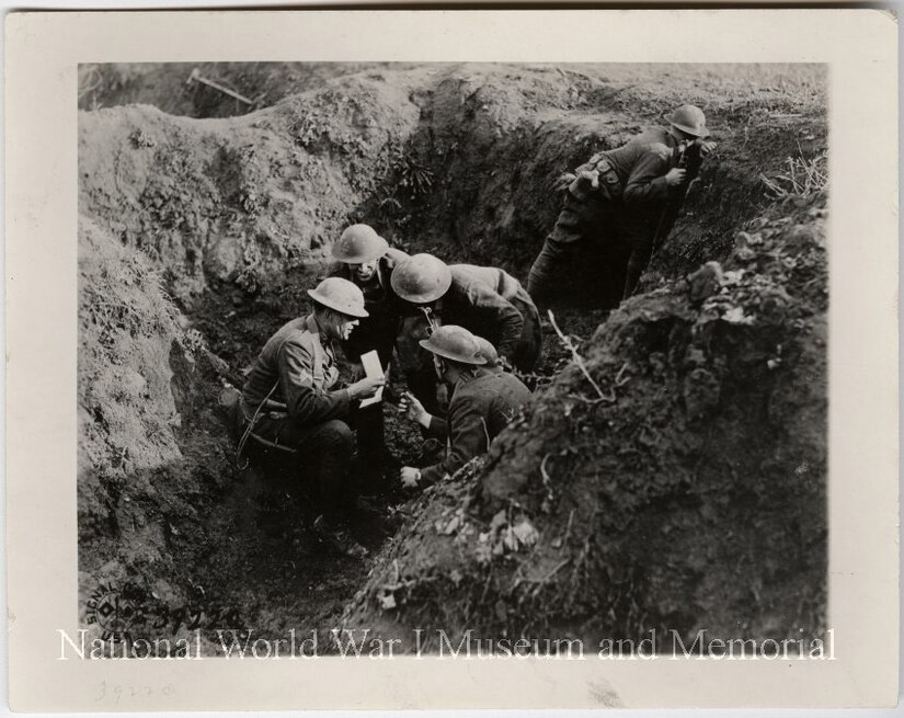 American troops discuss strategy in shell hole in France.