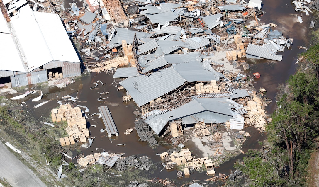 Aerial photo shows warehouses damaged by a hurricane that are surrounded by debris.