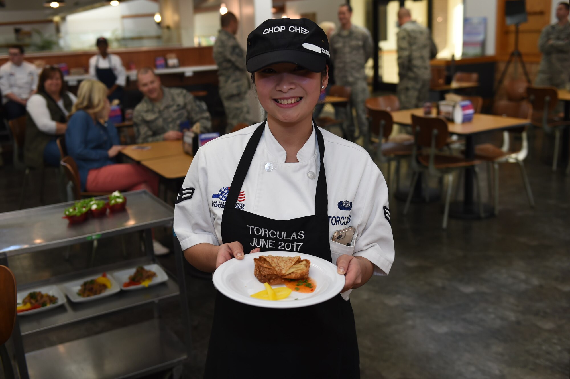 U.S. Air Force Airman 1st Class Michelle Vi Torculas, a food services specialist assigned to the 97th Force Support Squadron, presents the dish she prepared for the 2017 Chopped Chef Challenge, November 28, 2017, at Altus Air Force Base, Okla. The five competitors of the Hangar 97 cooking staff were given a basket containing six random ingredients to create a three-course meal within two hours. Torculas won the region two 2018 Arthur J. Myers Food Service Excellence Award for her hard work in events like this and in her career. (U.S. Air Force photo by Senior Airman Kirby Turbak)