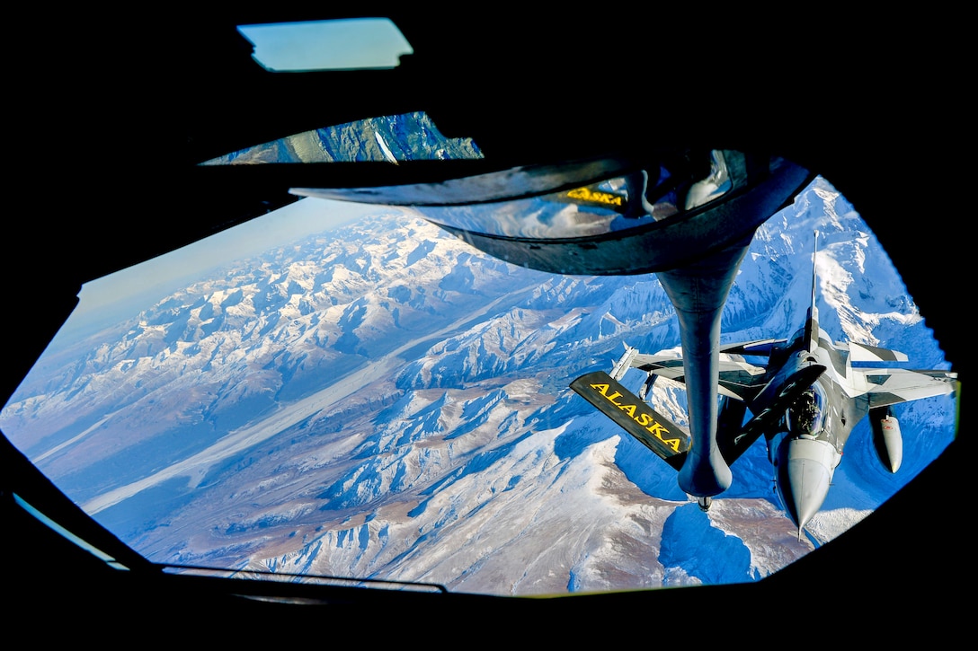 A plane lines up mid-air with a refueling pump attached to another plane.