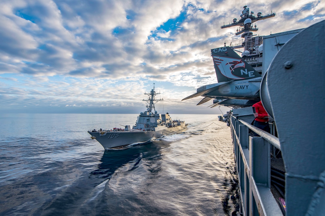 A navy ship refuels another navy ship.