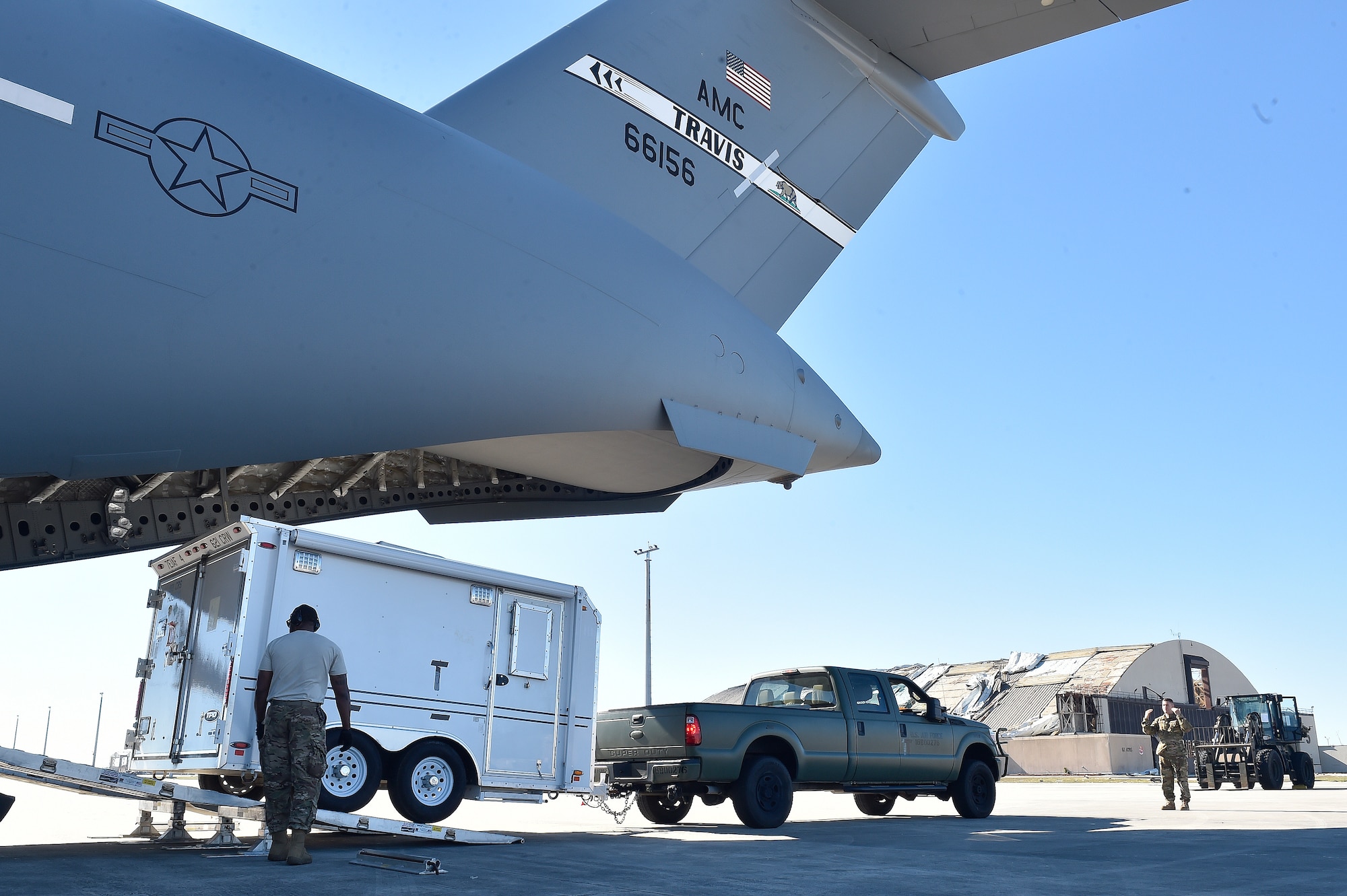 821st Contingency Response Group Airmen offload their mobile command and control trailer from a Travis Air Force Base C-17 Globemaster III, at Tyndall Air Force Base, Florida, Oct. 12, 2018. The mobility Airmen of this contingency response team deployed to assess damage and establish conditions for the re-initiation of airflow, bringing much needed equipment, supplies and personnel for the rebuilding of the base in the aftermath of Hurricane Michael. AMC equipment and personnel stand by across the nation to provide even more support upon request. (U.S. Air Force photo by Tech. Sgt. Liliana Moreno)