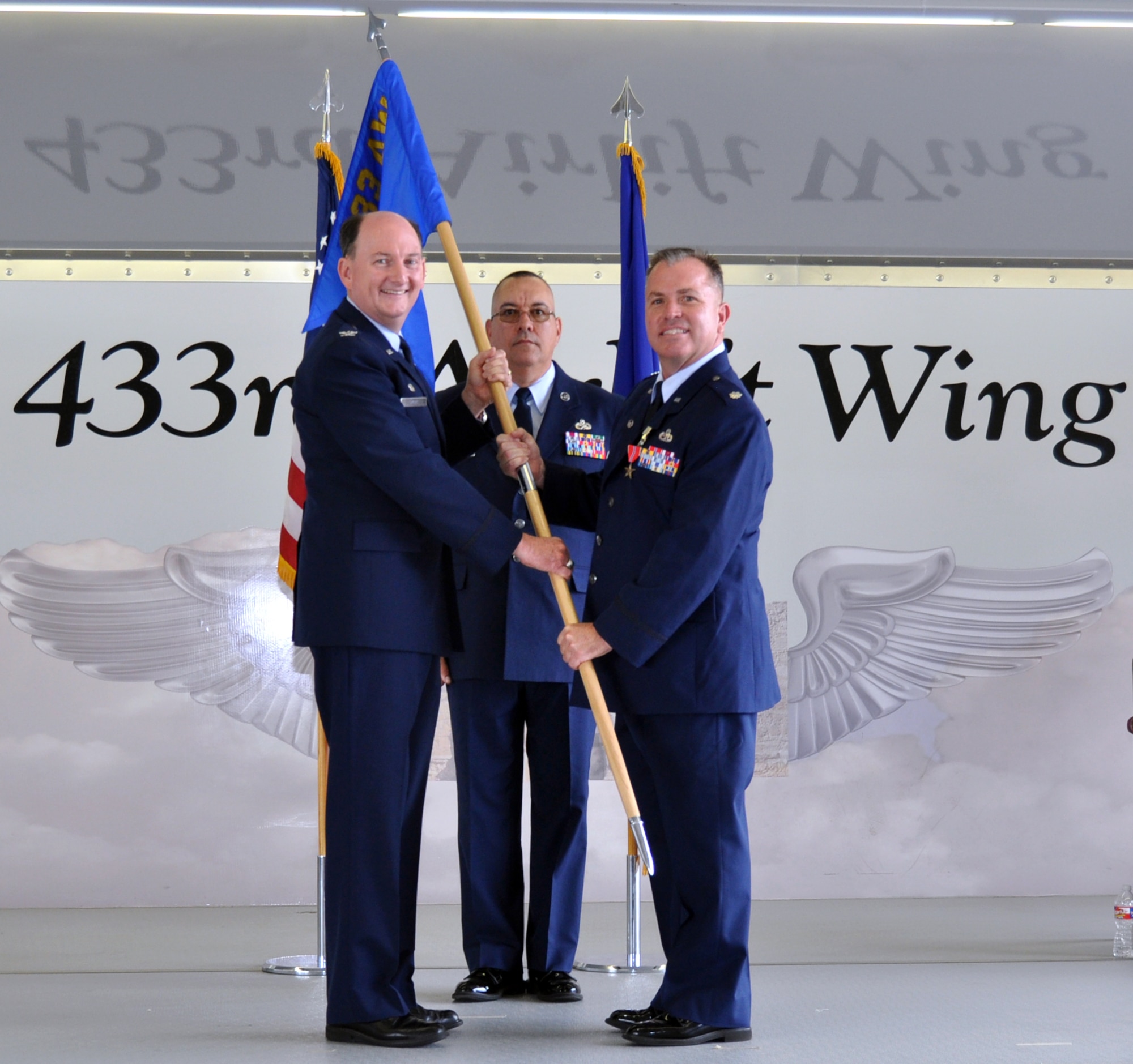 Col. Thomas K. Smith Jr., 433rd Airlift Wing commander passes the guidon to new 433rd Maintenance Group commander Lt. Col. Stuart L. Martin while Chief Master Sgt. Joseph Salomon, 433rd MXG superintendent, stands by Oct. 13, 2018 at Joint Base San Antonio-Lackland, Texas.