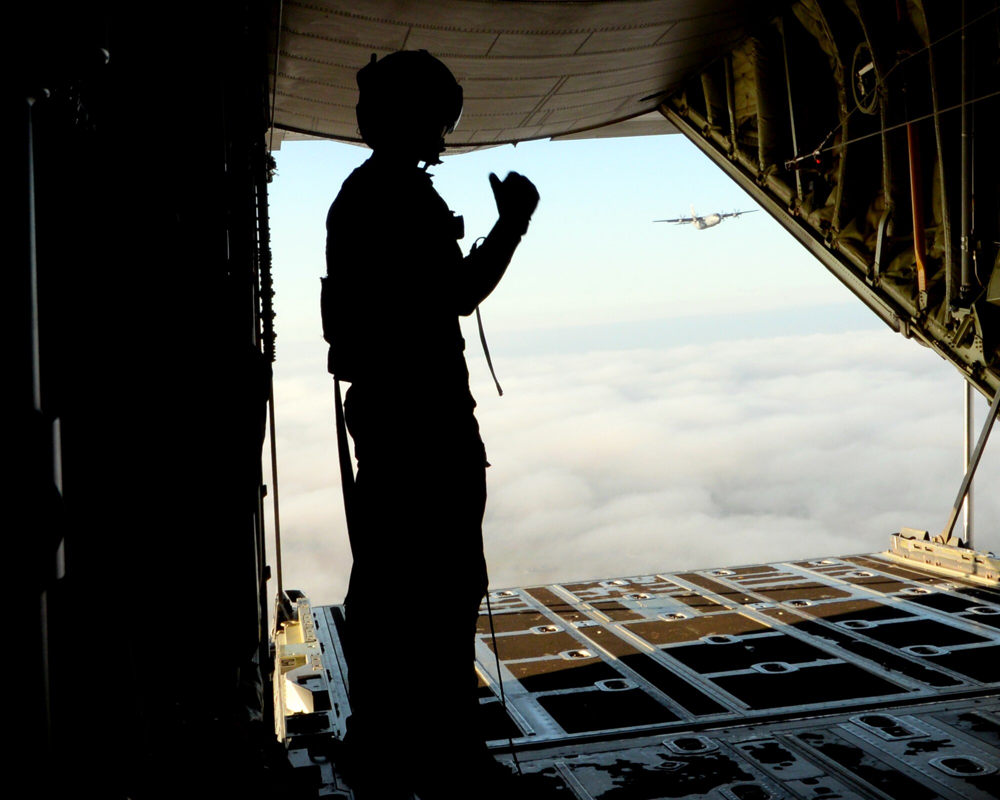 A 37th Airlfit Squadron loadmaster give the "okay" for parajumpers to begin their jump out of the C-130J Super Hercules over Chievres Air Base, Oct. 4, 2018. Two C-130s from the 37th AS executed the mission which were controlled by the 435th CRS in support of the NATO mission exercises. (U.S. Air Force photo by Airman 1st Class Ariel Leighty)
